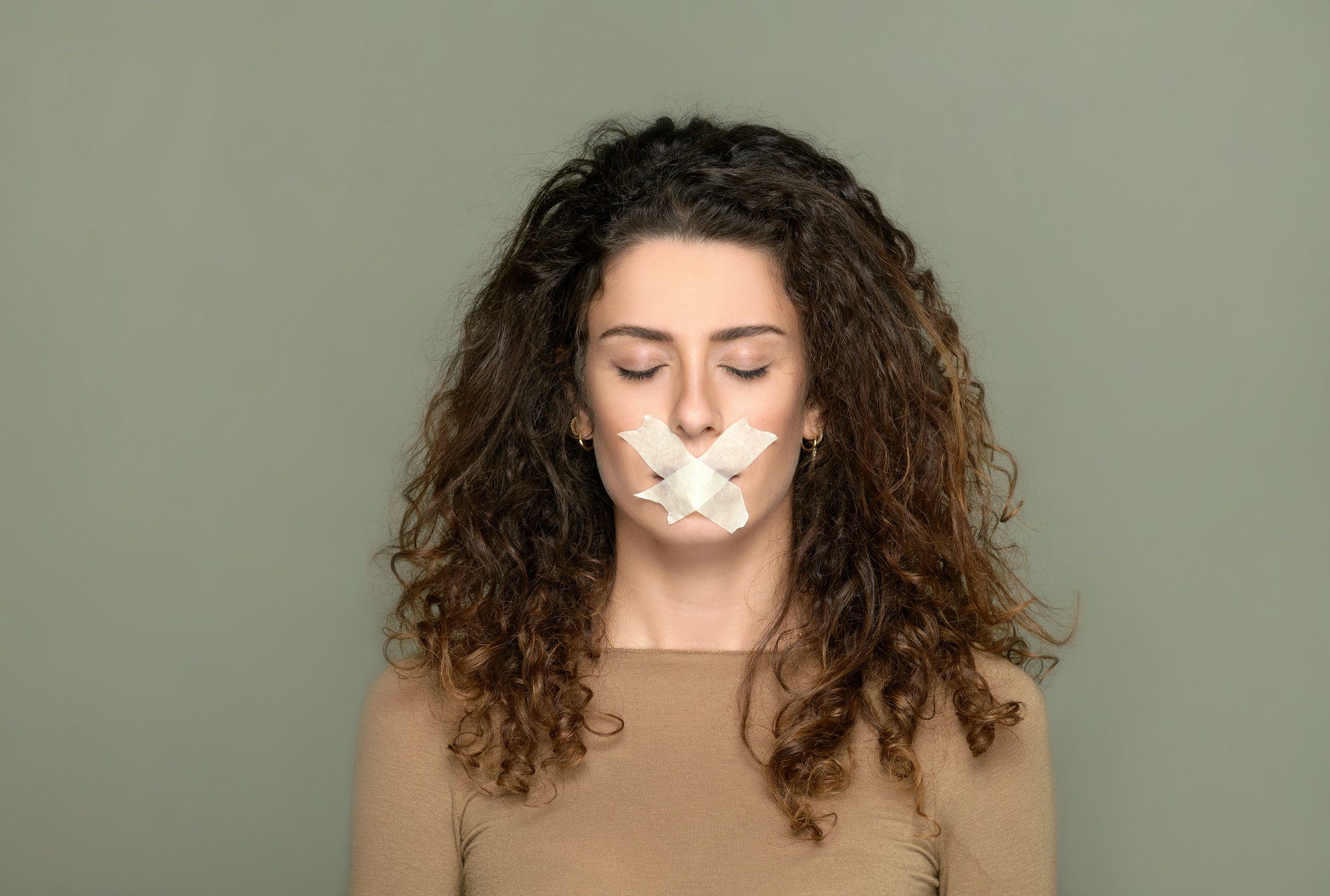 Young woman with closed eyes and taped lips