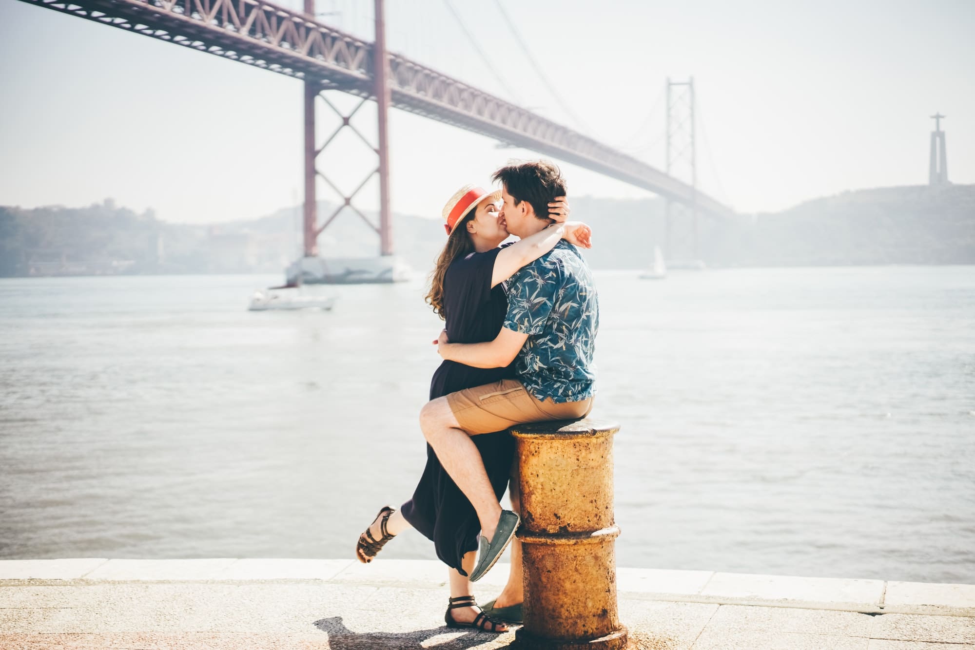 Romantic couple kissing in front of the bridge called April 25 in Lisbon