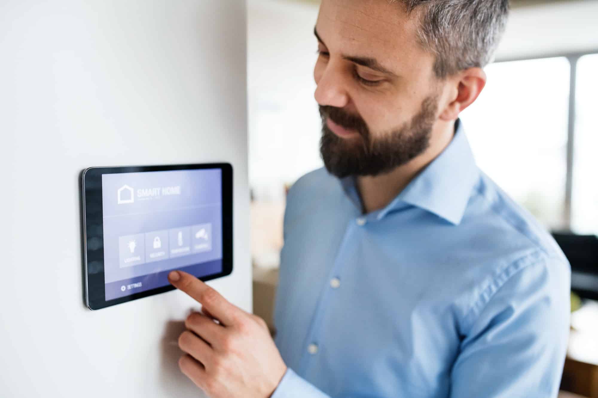 A man pointing to a tablet with smart home screen at home.