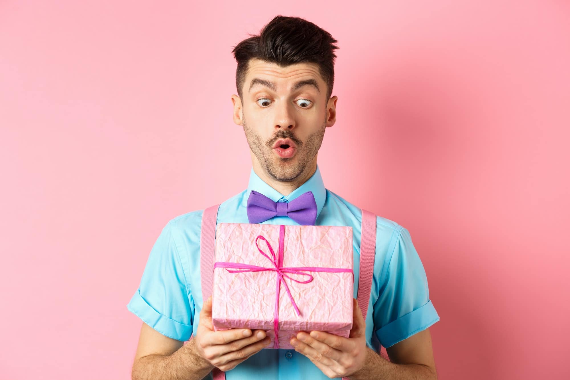 Holidays and celebration concept. Handsome guy in bow-tie receiving birthday gift, looking at