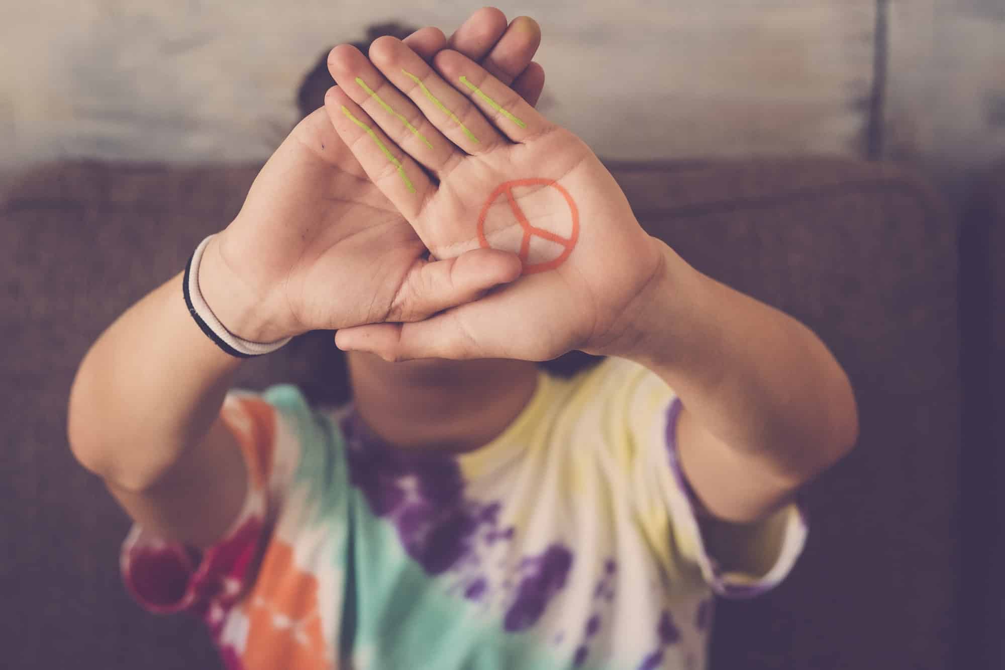 peace no war symbol painted on hand of young boy