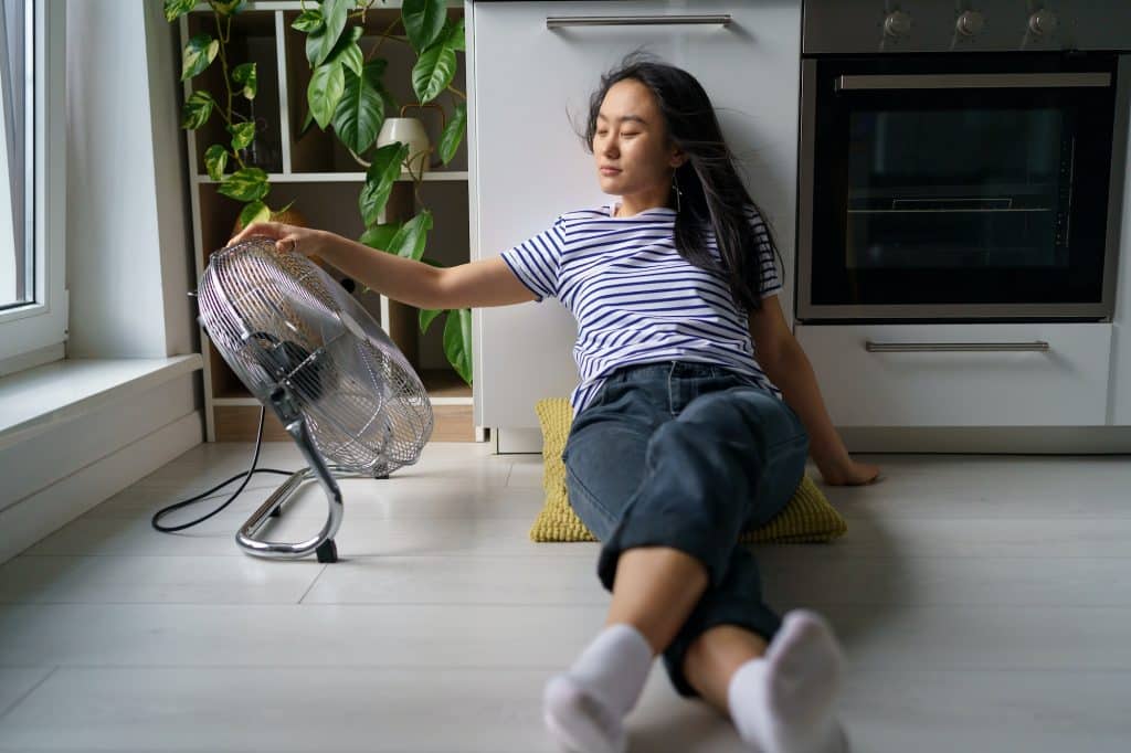 Tired overheated young Asian woman suffering from heat at home