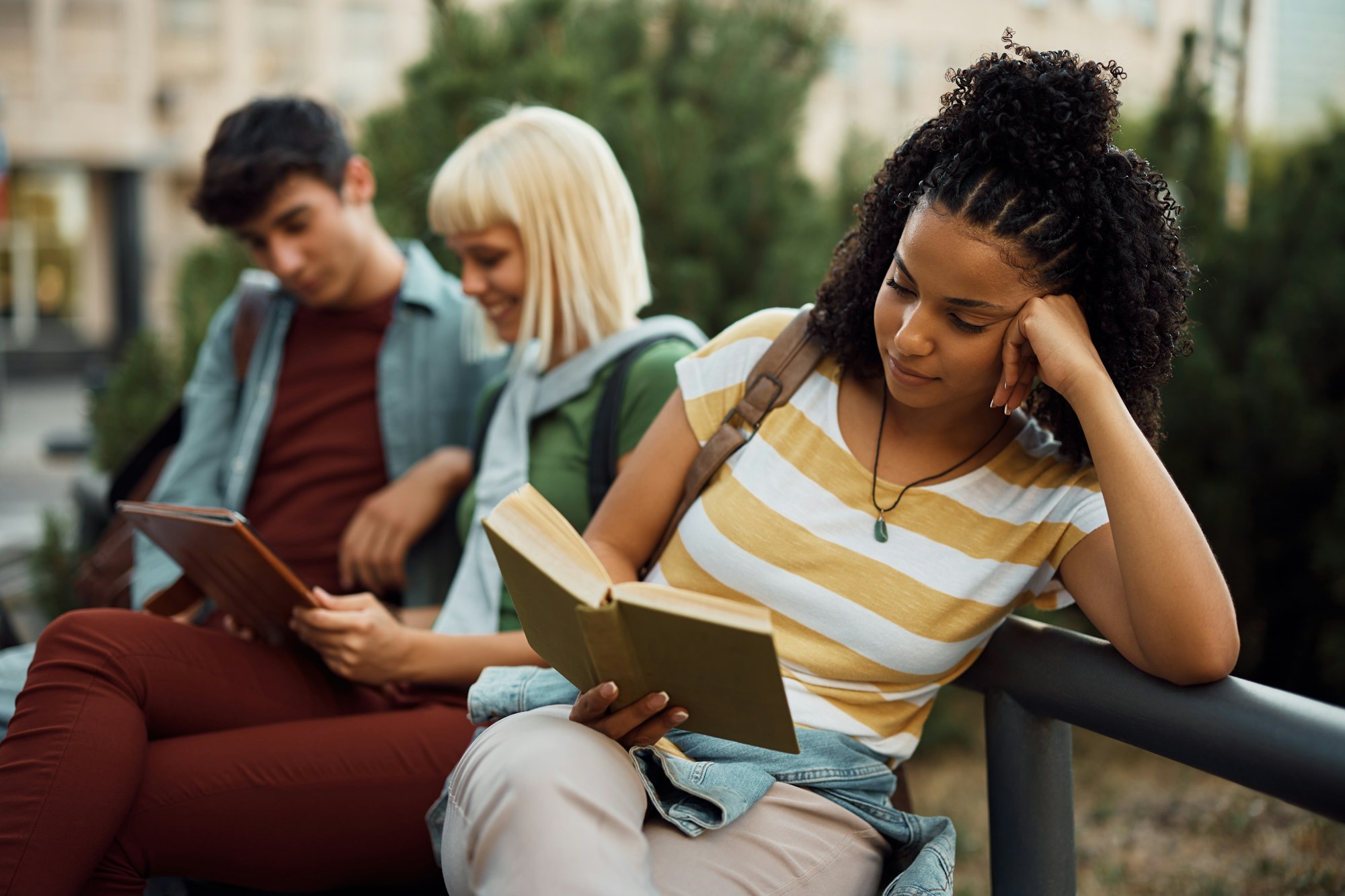 Young black woman reading a book at campus.