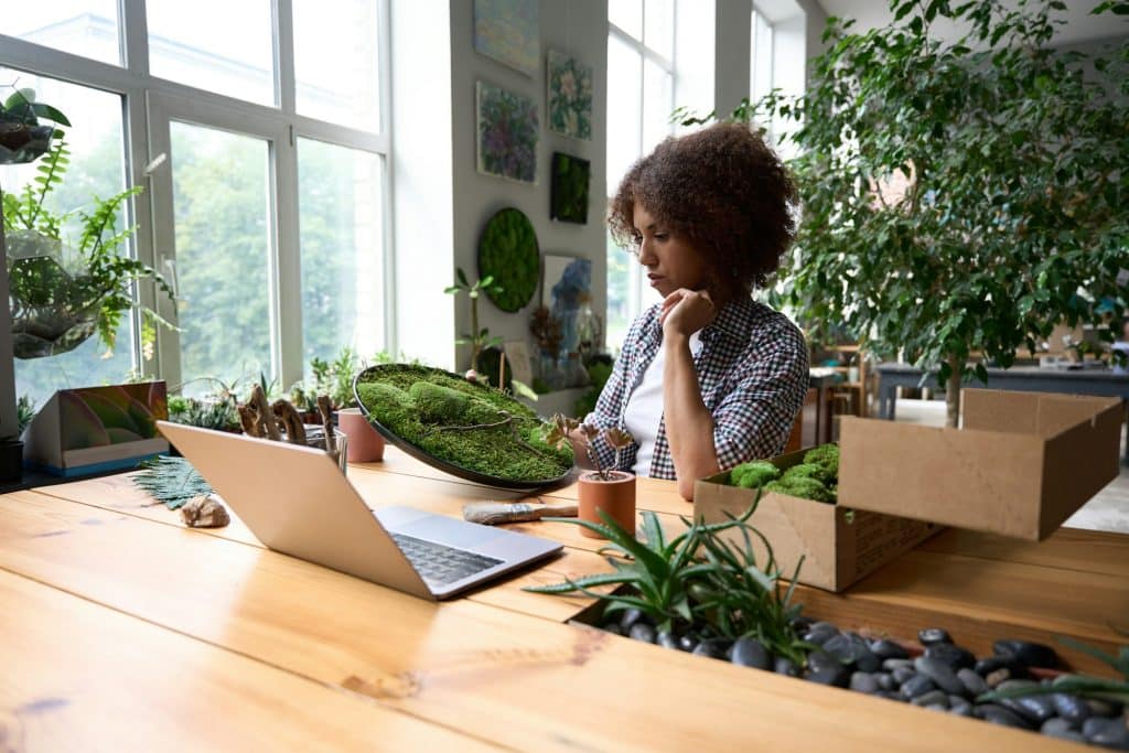 Cheerful woman enjoying work in florist office with moss