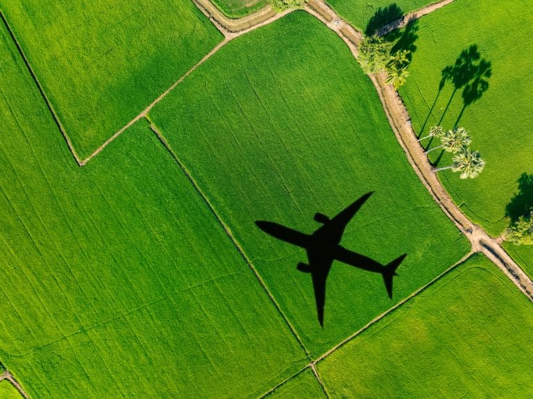 Shadow airplane flying above green field. Sustainable aviation fuel. Sustainable transportation